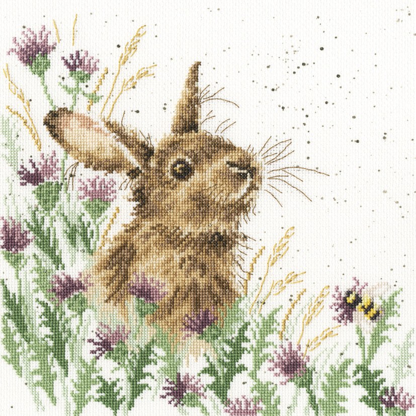 Cross stitch kit design of a brown rabbit surrounded by purple flowers and a bee in a meadow