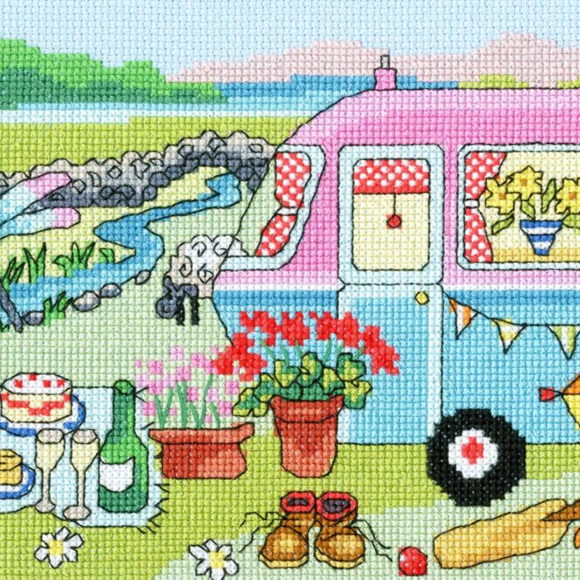 Caravan fun cross stitch kit featuring colorful caravan, picnic setup, dragonflies, sheep, and countryside scene