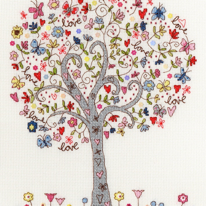 Colorful Love Tree cross stitch design with butterflies, flowers, hearts, and the word "love" on white Aida fabric