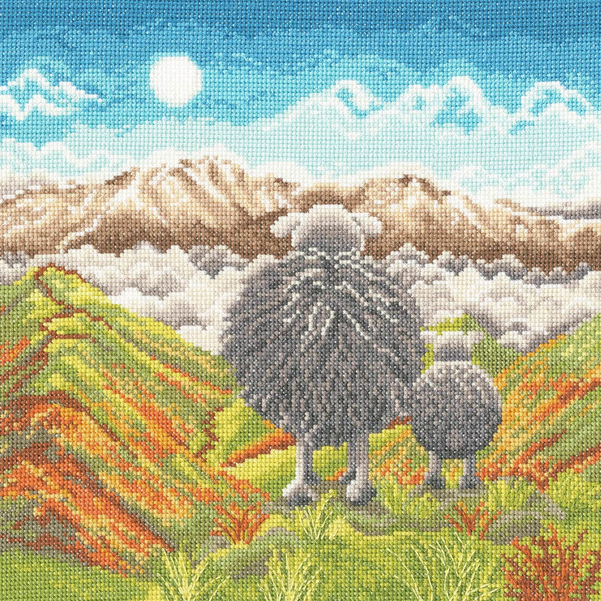On Top of the World cross stitch kit featuring sheep on a mountain landscape with blue sky and clouds.