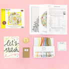 Spring wreath cross stitch kit with 14 count ice blue Aida, gold metallic thread, sequins, wooden Merry Christmas disc, and instructions